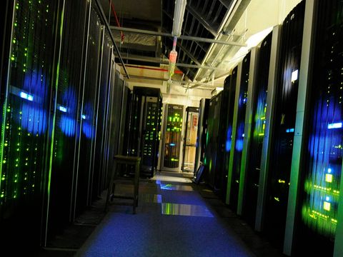 Gang zwischen Serverschränken mit grünen und blauen Statusleuchten in einem Rechenzentrum