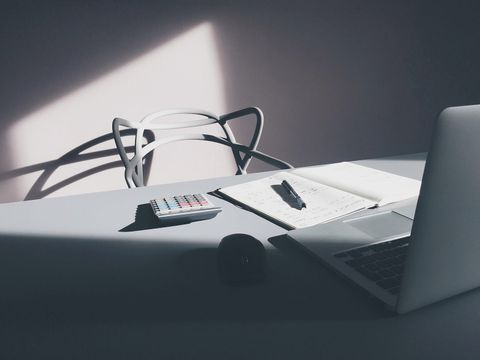 Taschenrechner, aufgeschlagenes Notizbuch mit Stift und Laptop auf einem hellen Schreibtisch